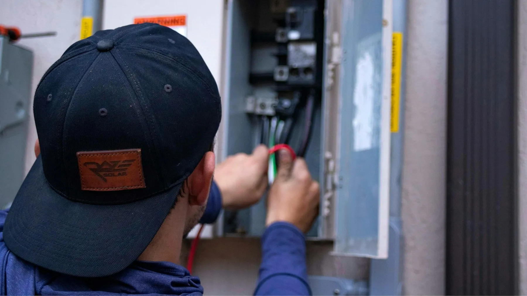 An electrician working inside an open panel.